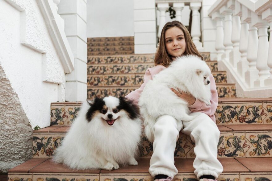 a girl with cute white pups sitting on the stairs